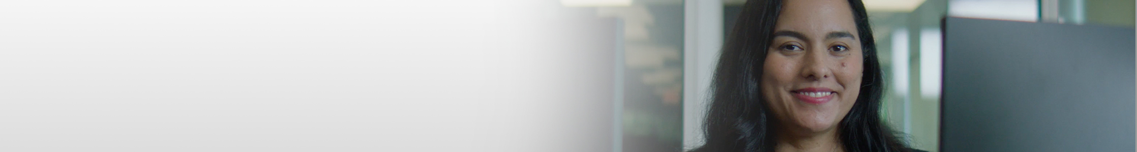 Woman sitting behind computer monitor looking straight ahead