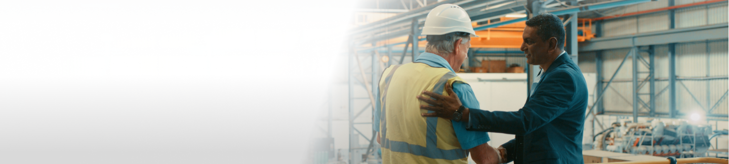 Business person shaking hands with factory worker